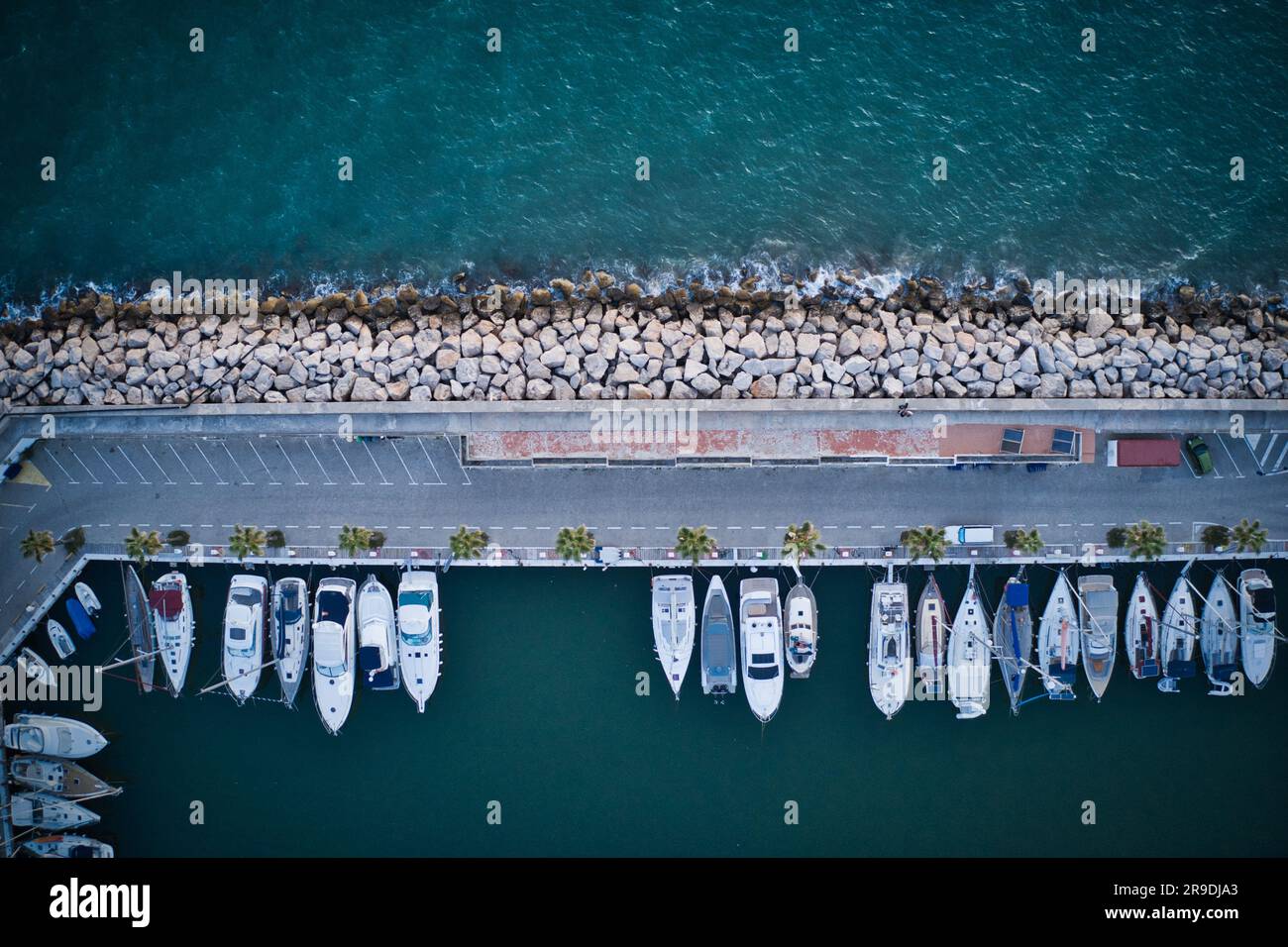 An aerial view of a calm body of water with boats lined up in a row near the shore Stock Photo