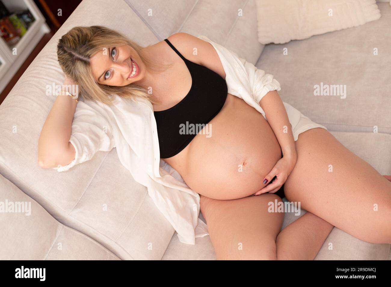 Young pregnant woman in studio lighting celebrating her first child Stock Photo