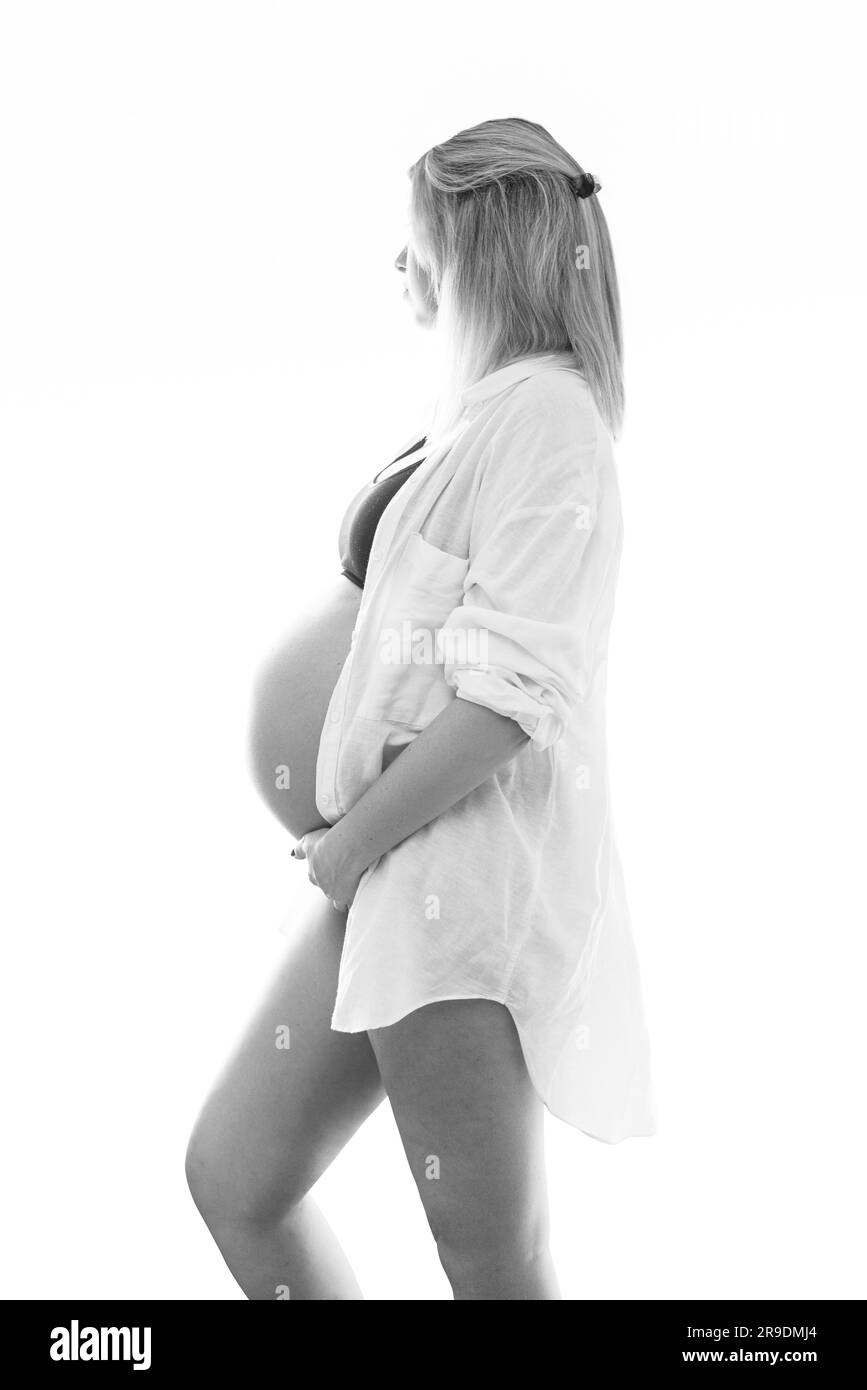 Young pregnant woman in studio lighting celebrating her first child Stock Photo