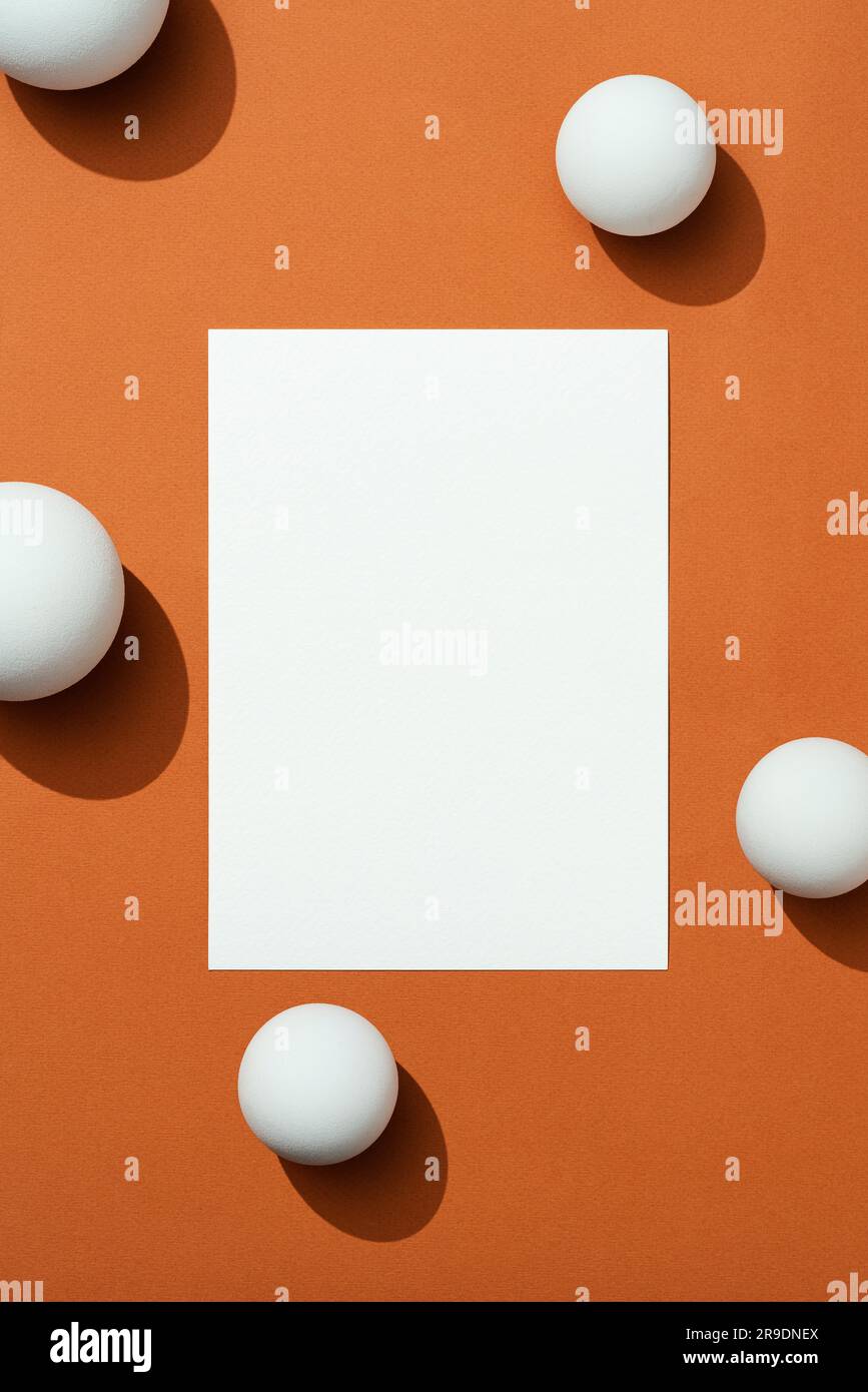 Blank white textured paper mockup with copy space on brown background. White spherical objects on background. Directly above high angle shot. Stock Photo