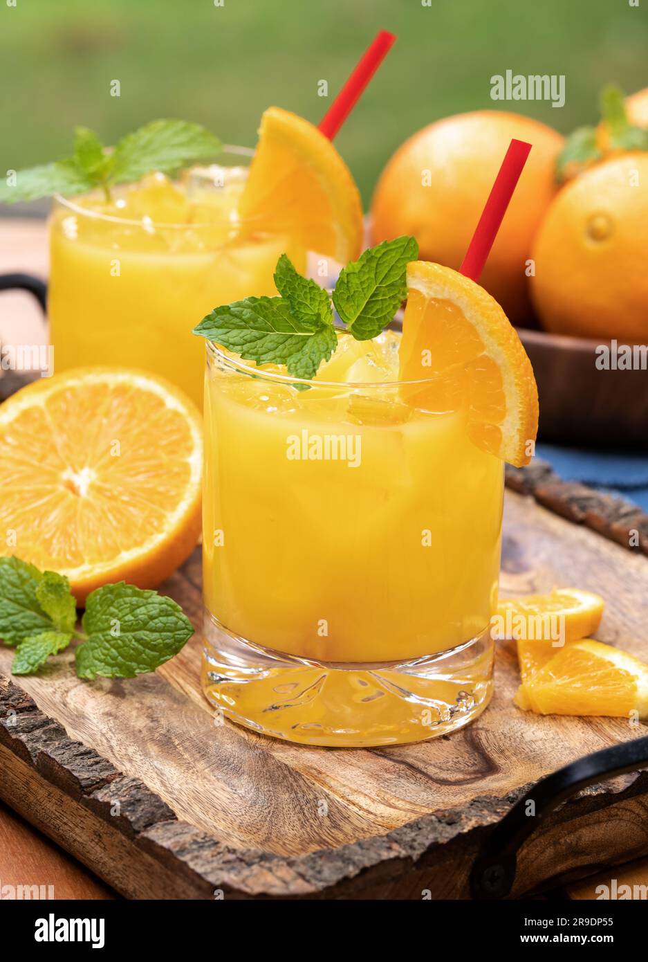 Orange juice cocktail with mint and orange slices outdoors on wooden tray Stock Photo