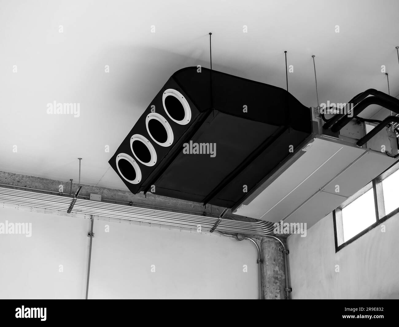 Black machine, modern air conditioning ceiling mounted ventilation system decoration on ceiling near electrical wiring steel pipes in old white constr Stock Photo