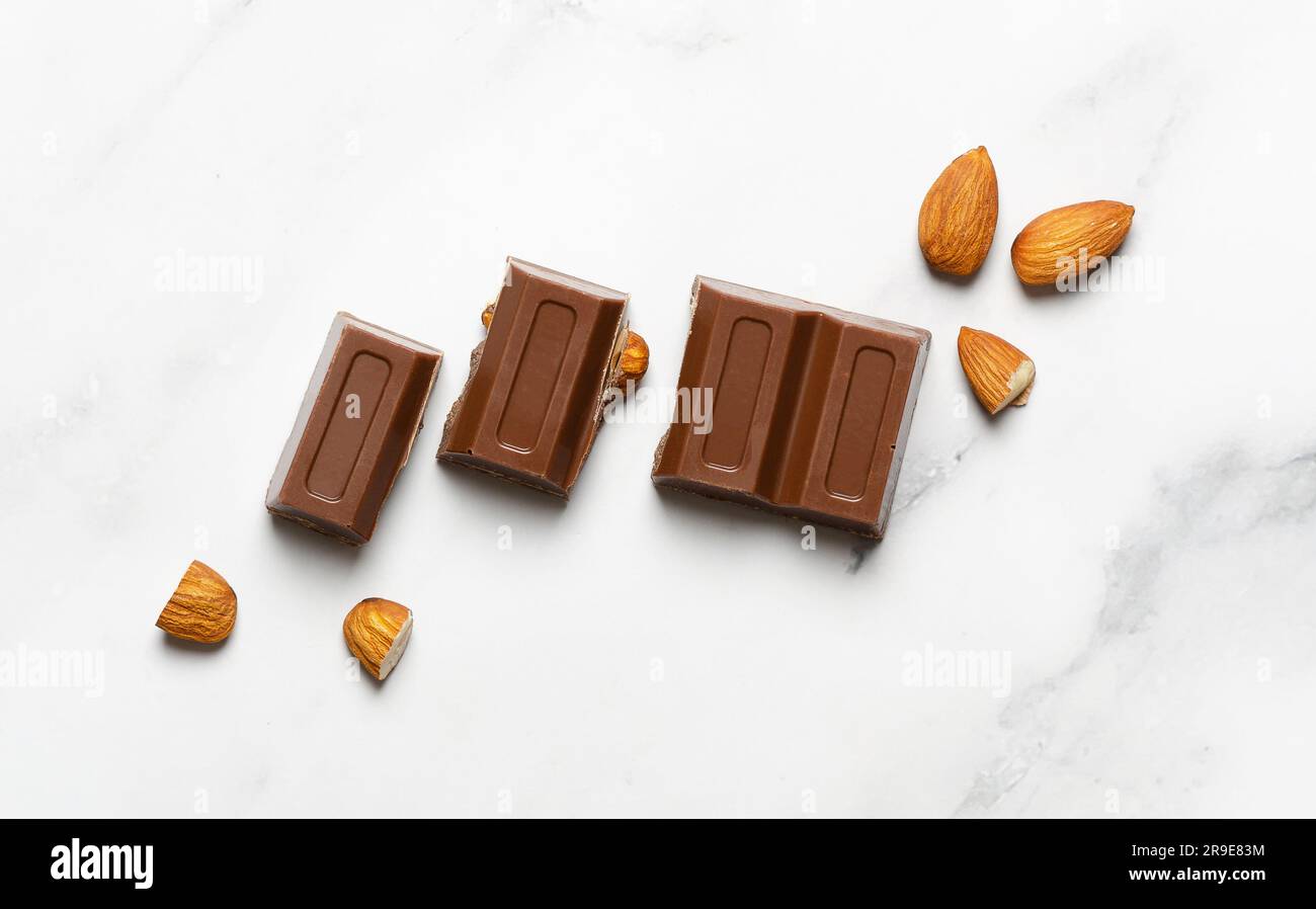 Milk chocolate with almonds on marble background. Stock Photo