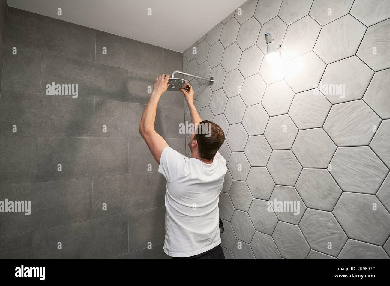 Male worker fixing bathroom showerhead while working on bathroom