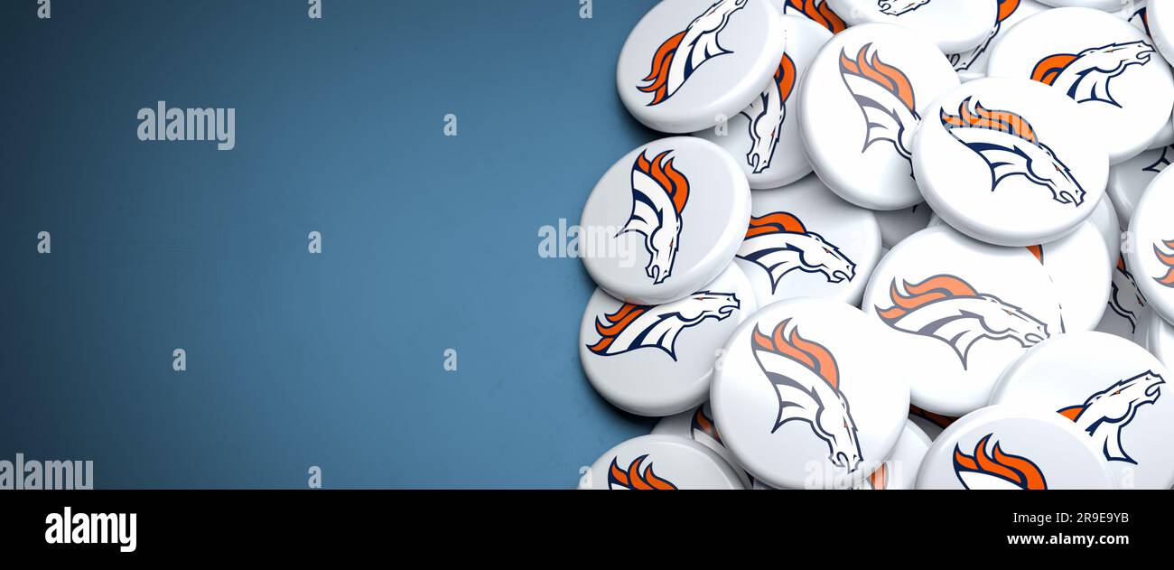 Logos of the American Football Team Denver Broncos on a heap on a table. Stock Photo