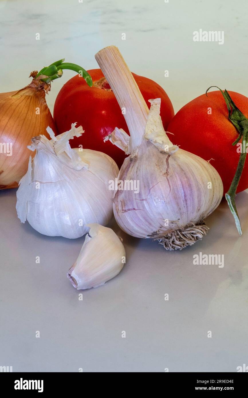 Still life of garlic, onion, and vine, ripened tomatoes on the kitchen counter, 2023, USA Stock Photo