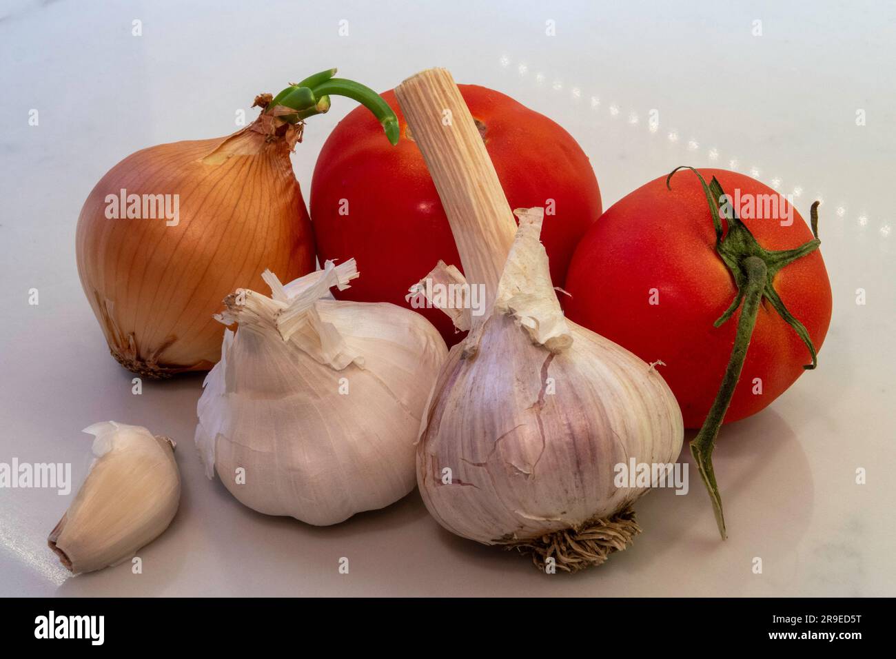 Still life of garlic, onion, and vine, ripened tomatoes on the kitchen counter, 2023, USA Stock Photo