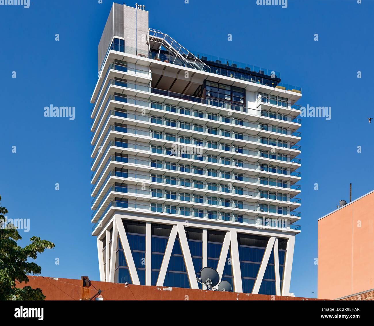 The William Vale hotel rises over truss-enclosed office floors, which rise above a two-story public, retail, and event venue podium. Stock Photo