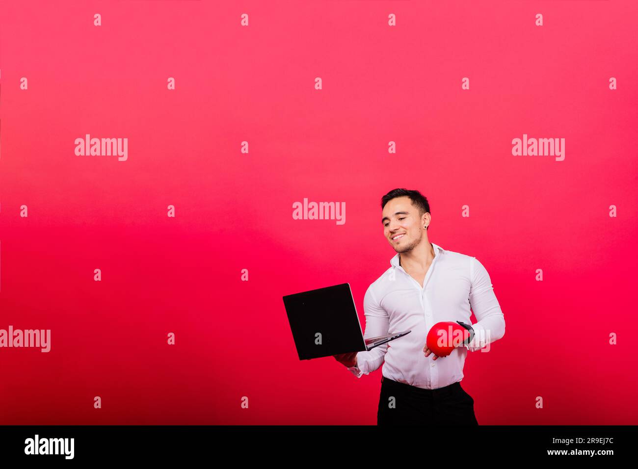 Guy in boxing gloves and formalwear punch computer isolated on red ...