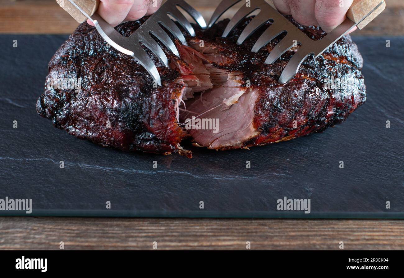Fresh whole pulled pork is torn apart with forks Stock Photo