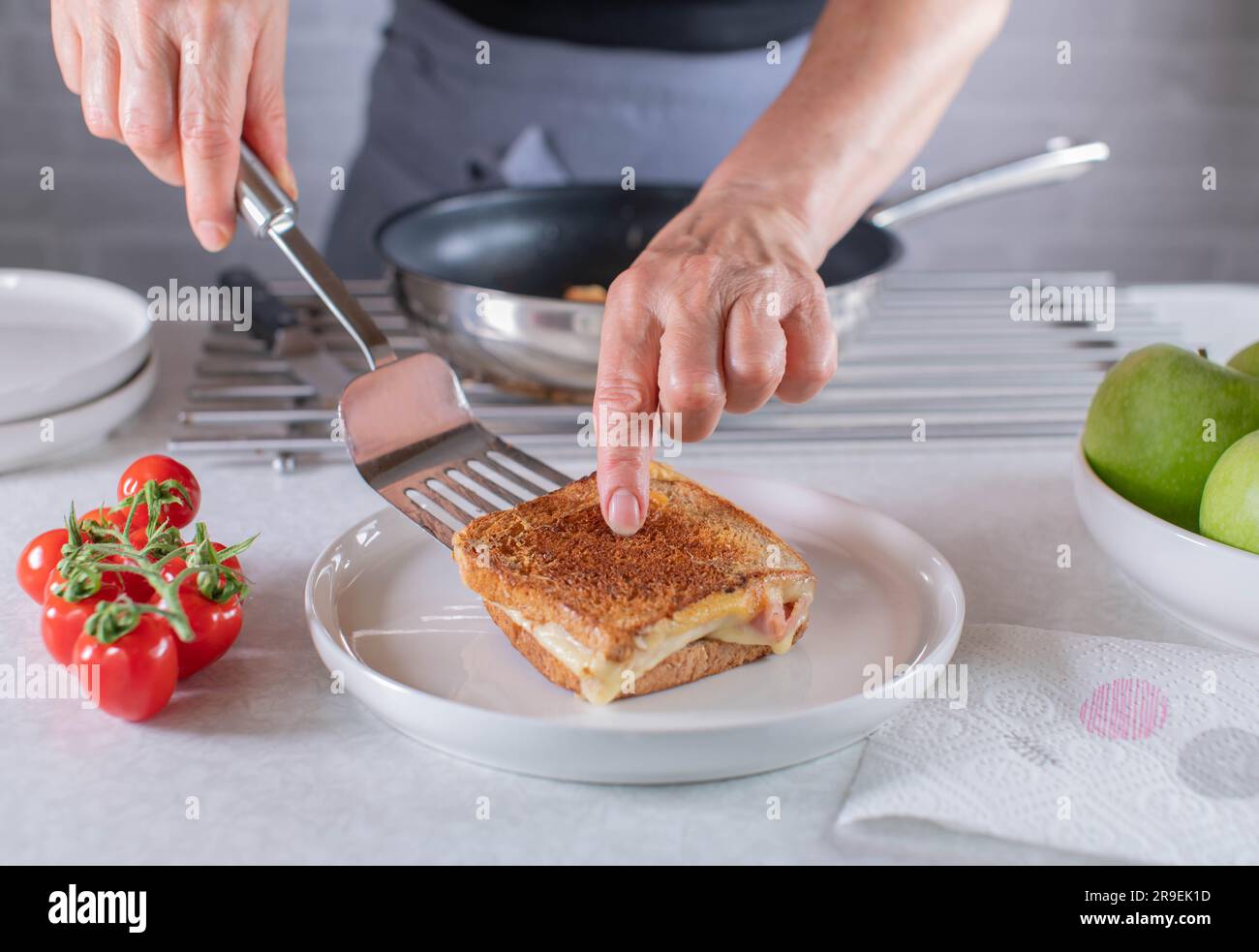 Woman with apron serving a fresh and hot ham and cheese sandwich on a plate Stock Photo