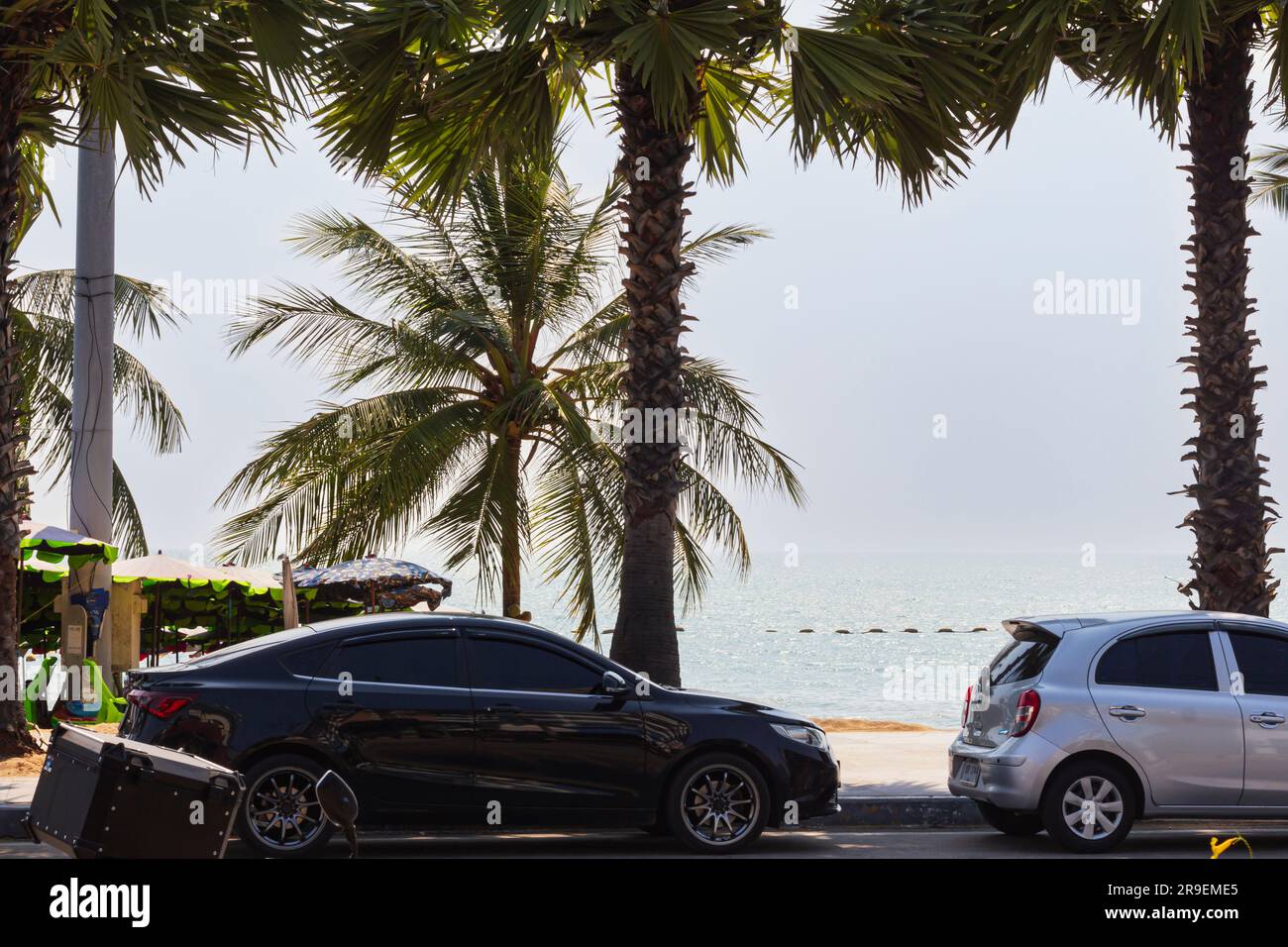 Empty sunny sea promenade with palm trees, cars and sea in background, selective focus, asia lifestyle. Tourist embankment of tropical Pattaya on sunn Stock Photo