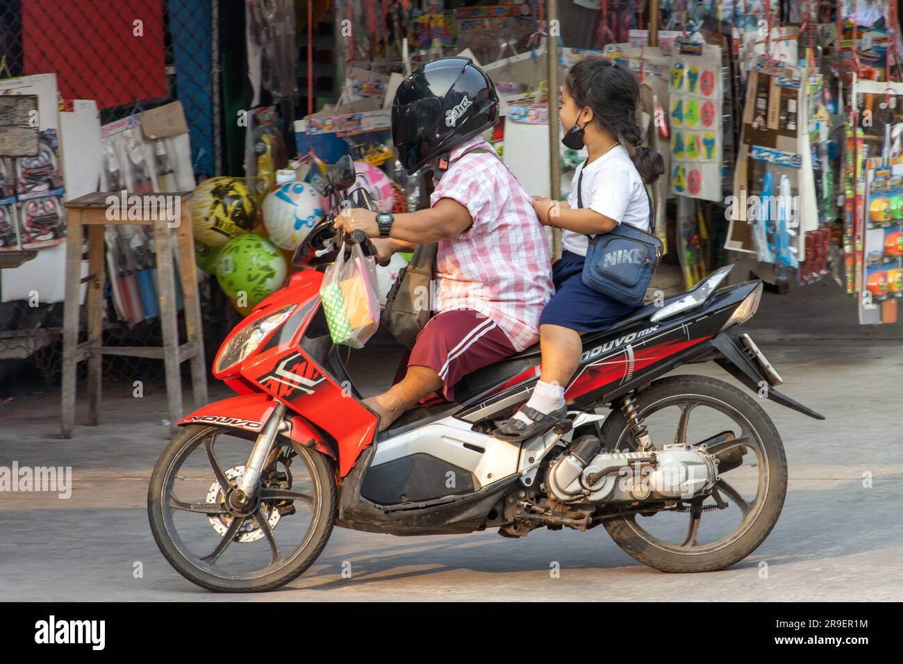 SAMUT PRAKAN, THAILAND, MAR 03 2023, A couple of small stature people ride a motorcycle Stock Photo