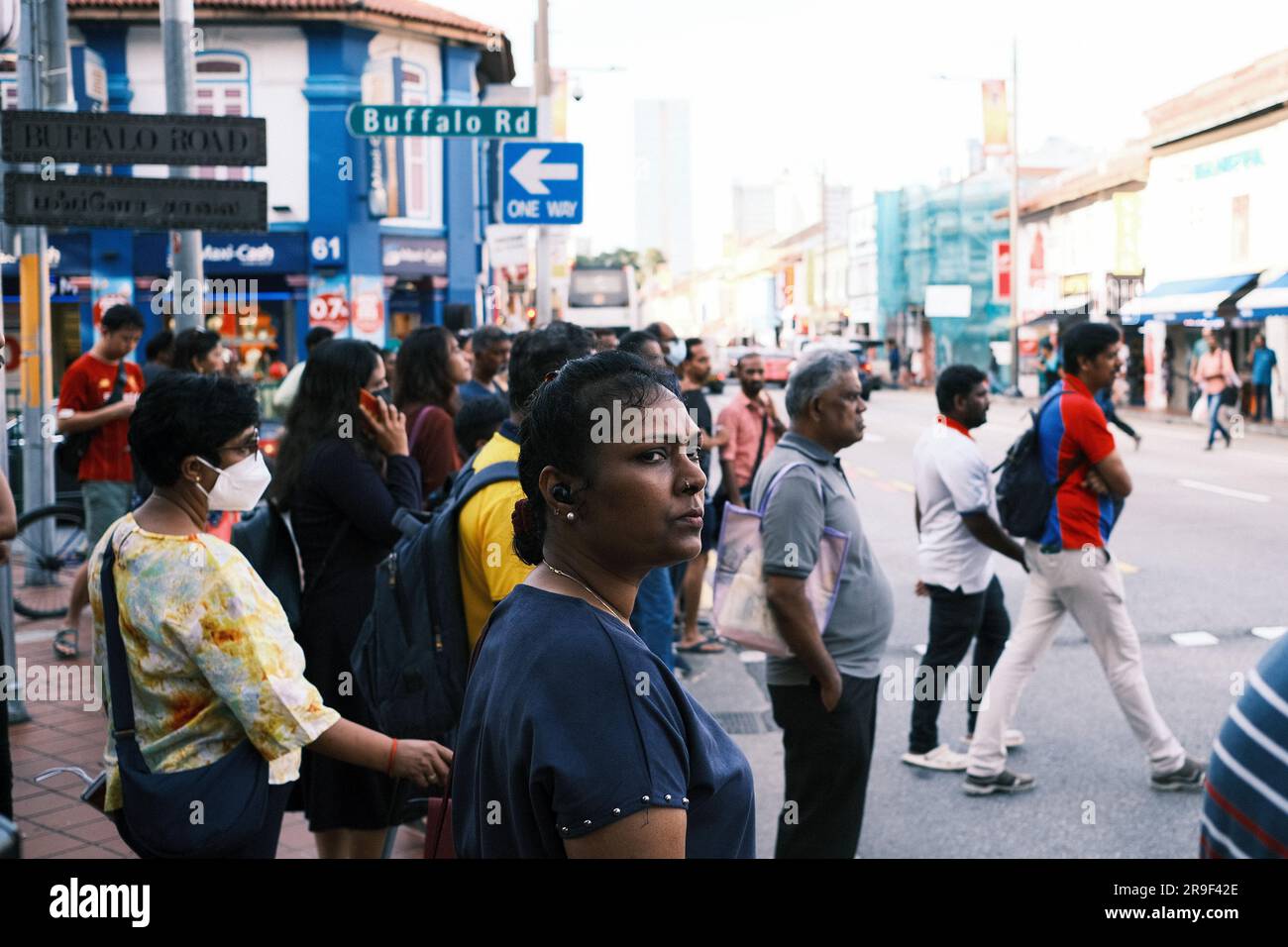 A woman crossing a busy city street with a diverse crowd of people in the background Stock Photo