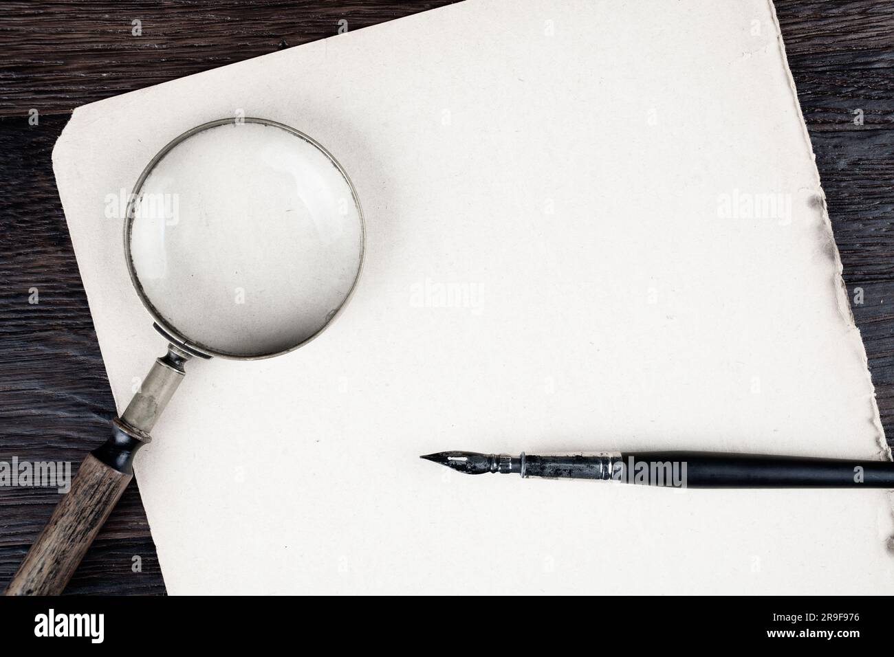 Antique vintage magnifying glass with old ink feather pen on paper ...