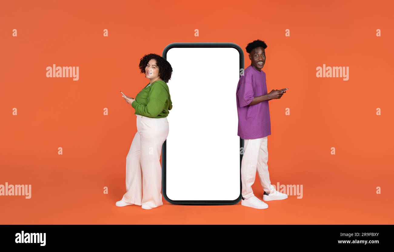 Cheerful young interracial couple using cell phones Stock Photo