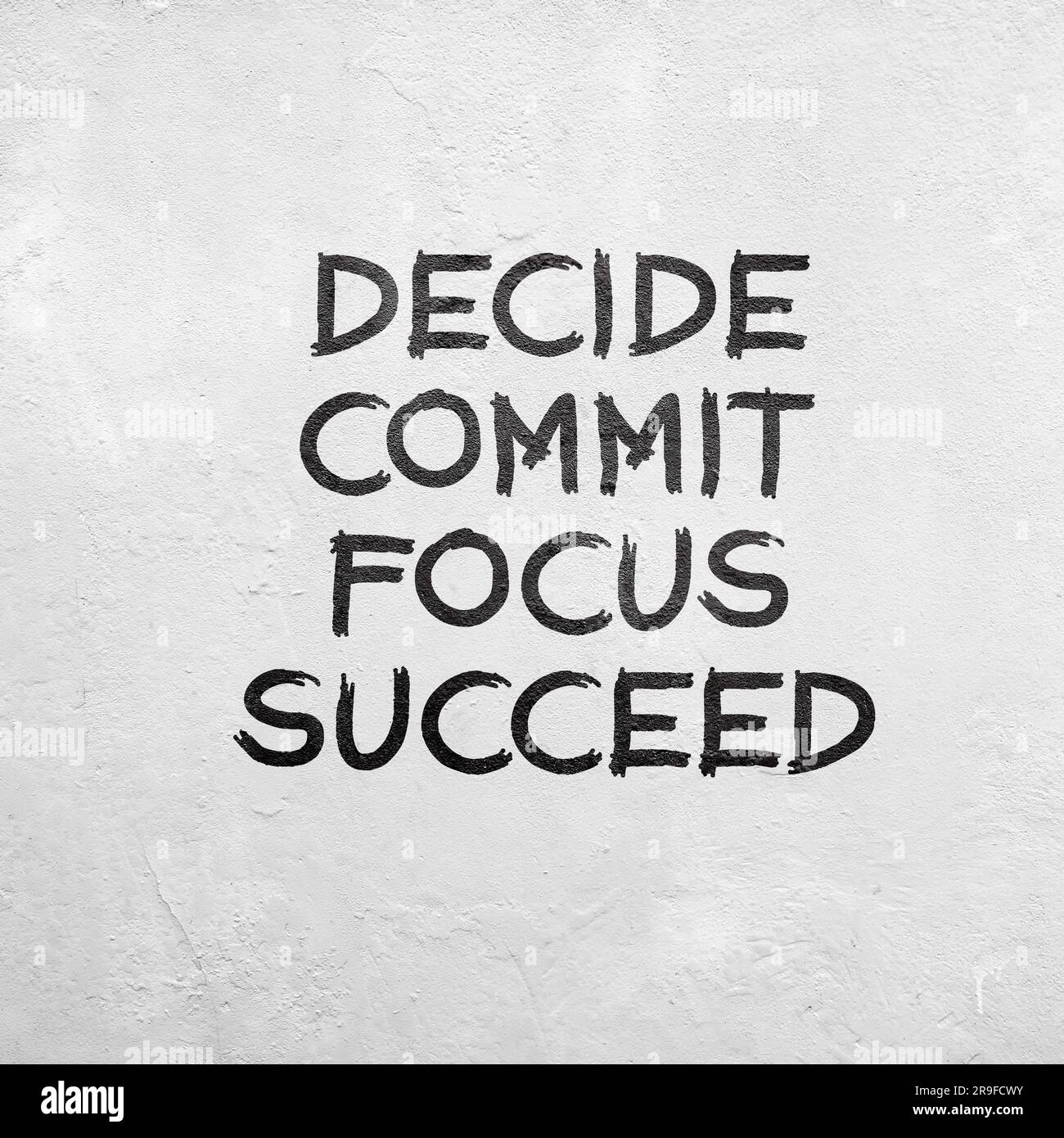 White concrete wall with inspirational quotes decide, commit, focus