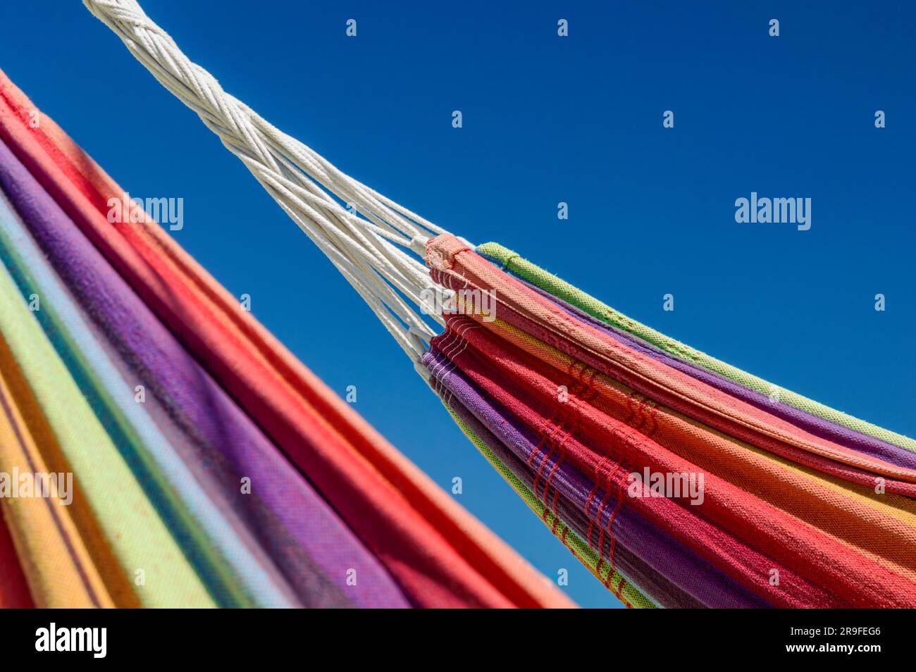 Close-up image of two rainbow-colored hammocks against the blue sky Stock Photo