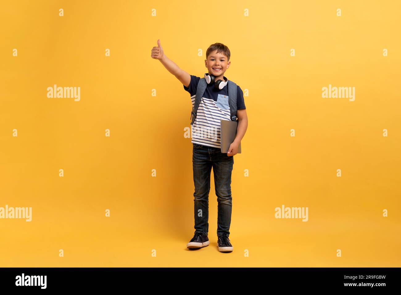 Cute schoolboy showing thumb up and smiling Stock Photo - Alamy