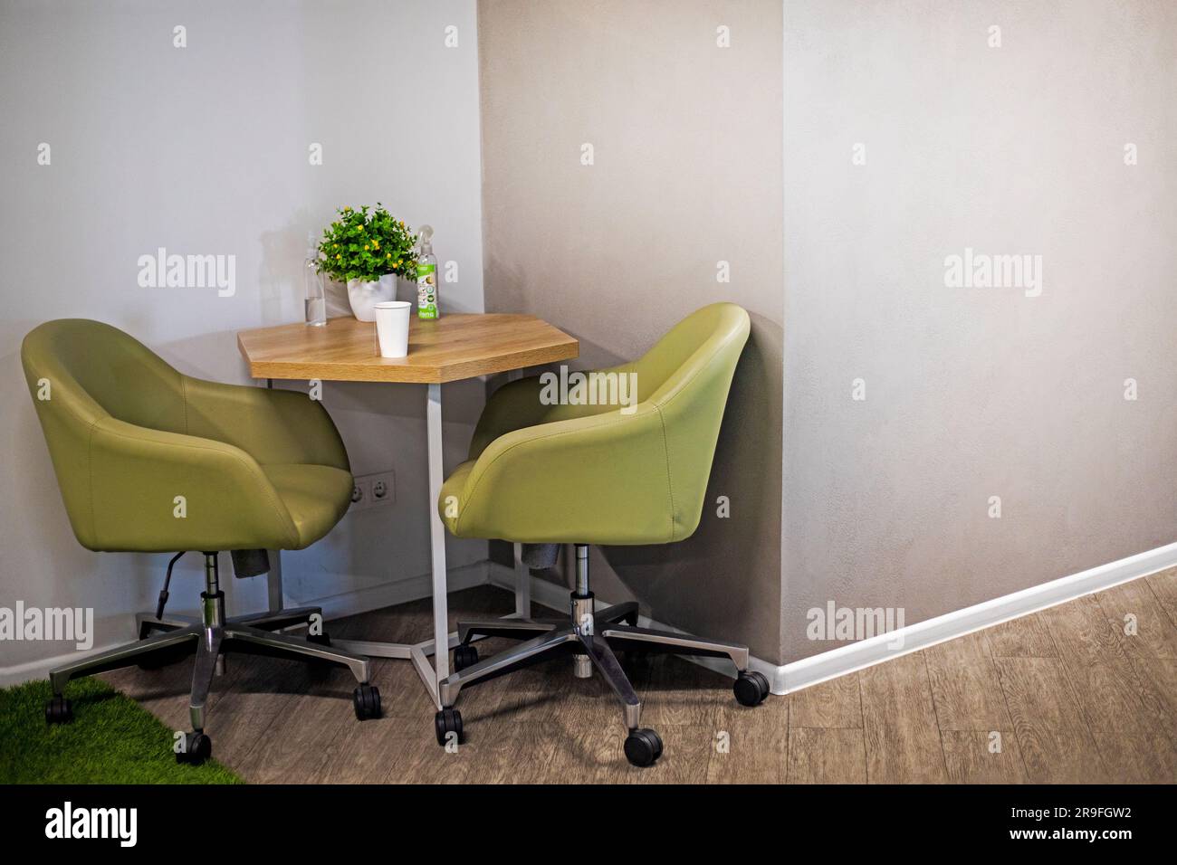 table with green office chairs in the corner of a concrete wall in a modern office interior. Snack area for office staff Stock Photo