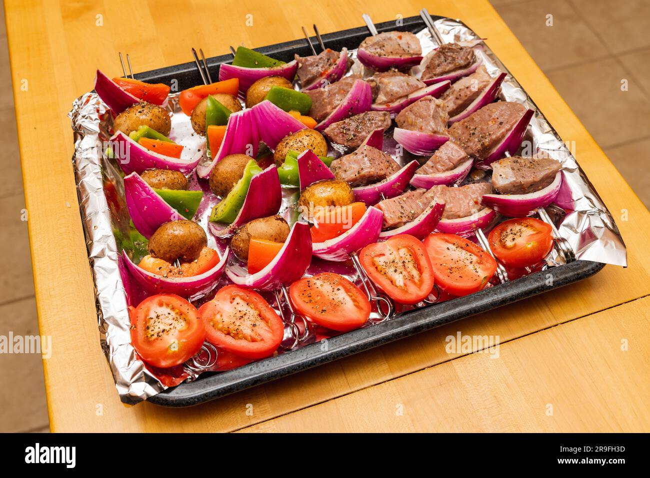 Beef and vegetable kabobs ready for summer grilling. Colorful tray of shish kabobs on wooden table. Stock Photo