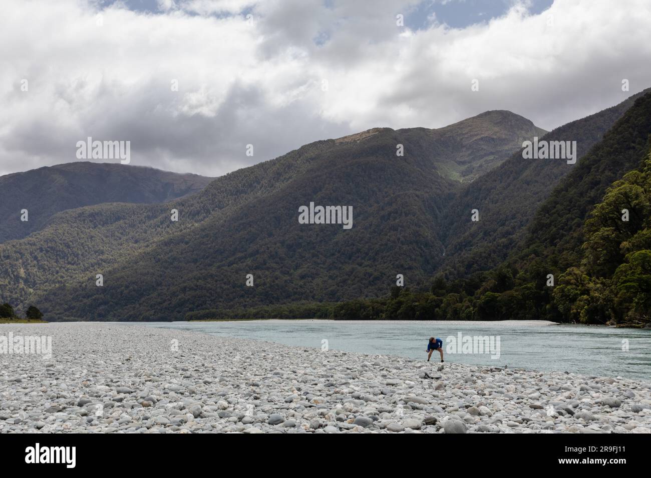 Tourist in the riverbed in Summer in the Haast River Pass Valley in New Zealand South Island Mount Aspiring National Park. Photo: Rob Watkins Stock Photo