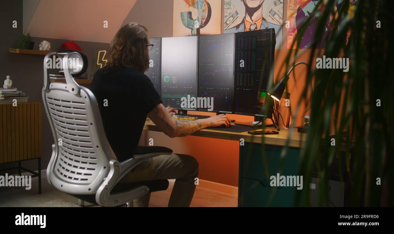 Successful trader watches real-time stocks, exchange market charts on multi- monitor computer, turns around and looks at camera. Man works remotely in  investment at home office. Cryptocurrency trading Stock Photo - Alamy