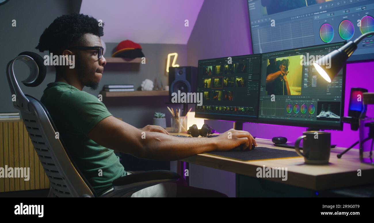 African American video maker edits action movie, makes color grading, works at home. Software interface with RGB tools and wheels on computer and big digital screen. Concept of film post production. Stock Photo