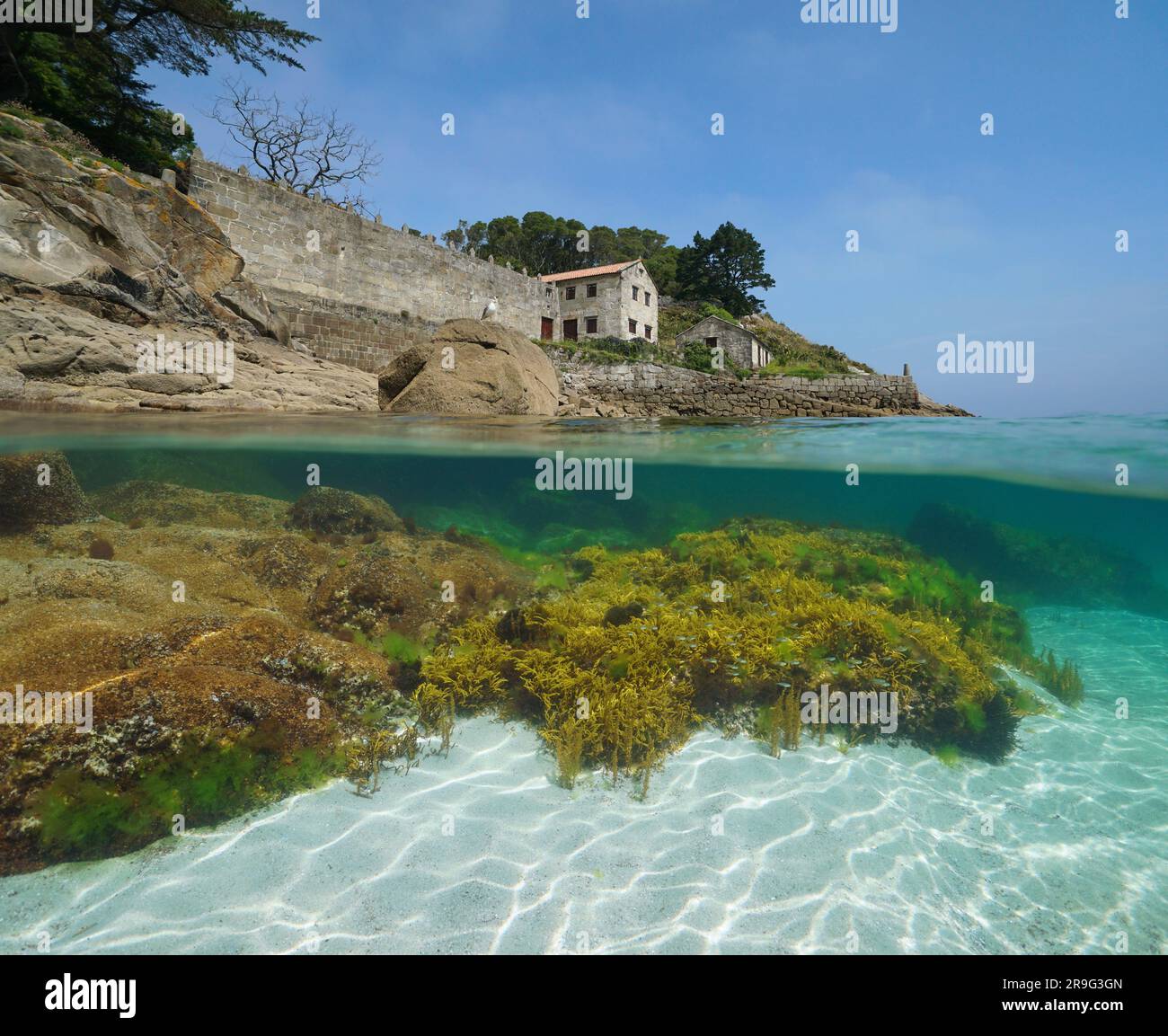Spain, Galicia, old coastal house with stone wall and slipway on the shore of the Atlantic ocean, split view over and under water surface, Rias Baixas Stock Photo