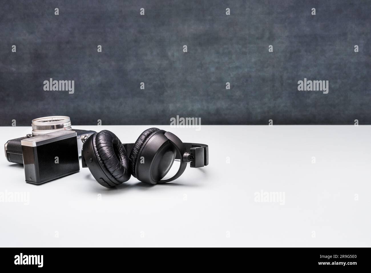 black over-ear headphones next to a vintage camera with flash Stock Photo