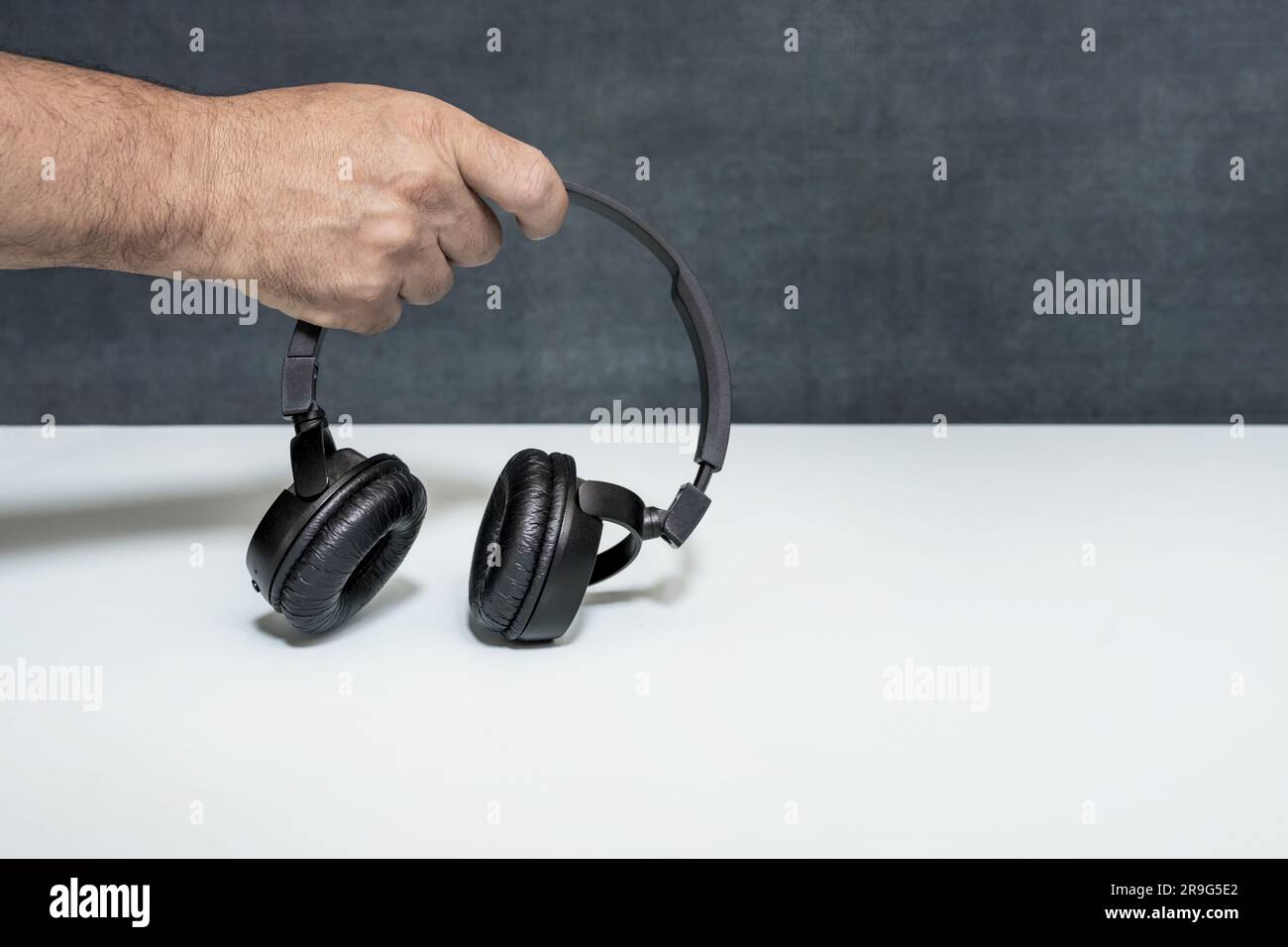 A hand holding a black over-ear wireless headphones Stock Photo