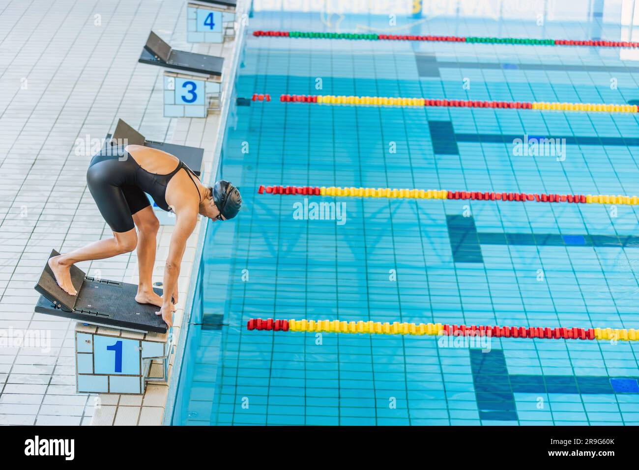 Professional female swimmer preparing and jumping off the starting