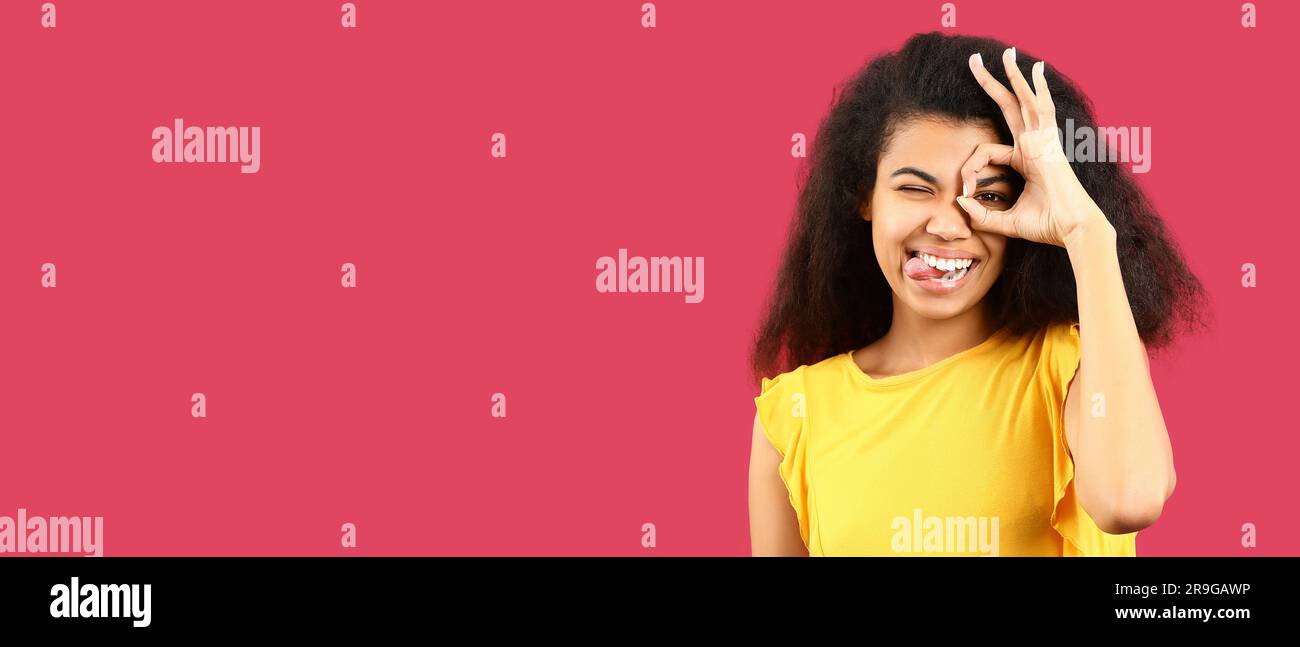 Happy African-American woman showing OK gesture on pink background with ...