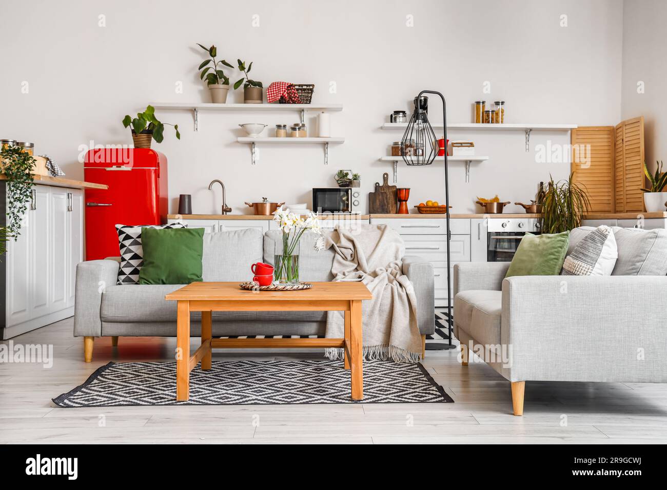 Interior of light kitchen with red fridge, counters, shelves, table and