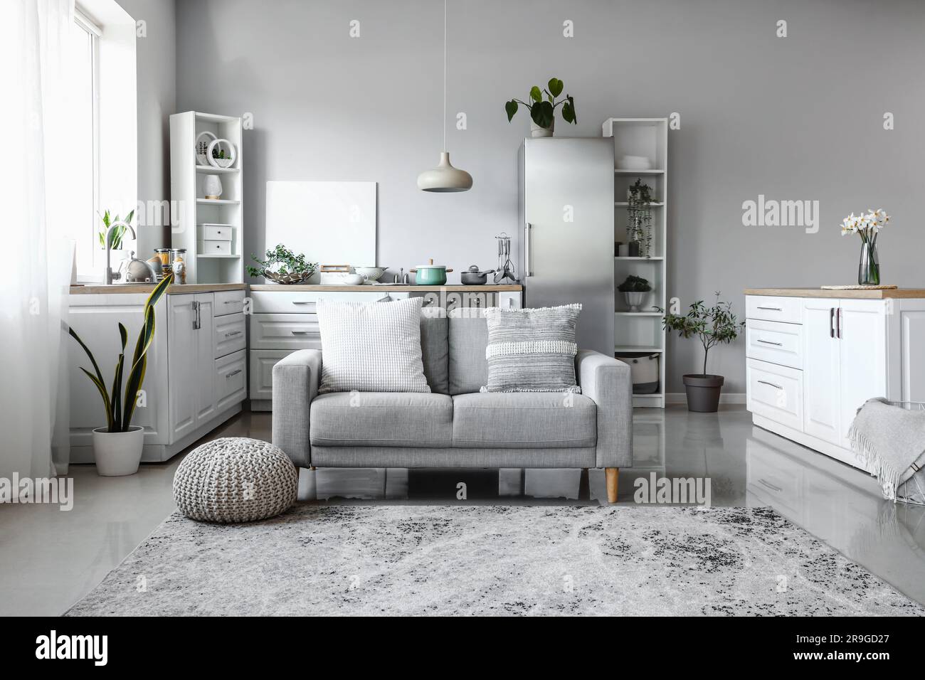 Interior of light kitchen with stylish fridge, counters, sofa and