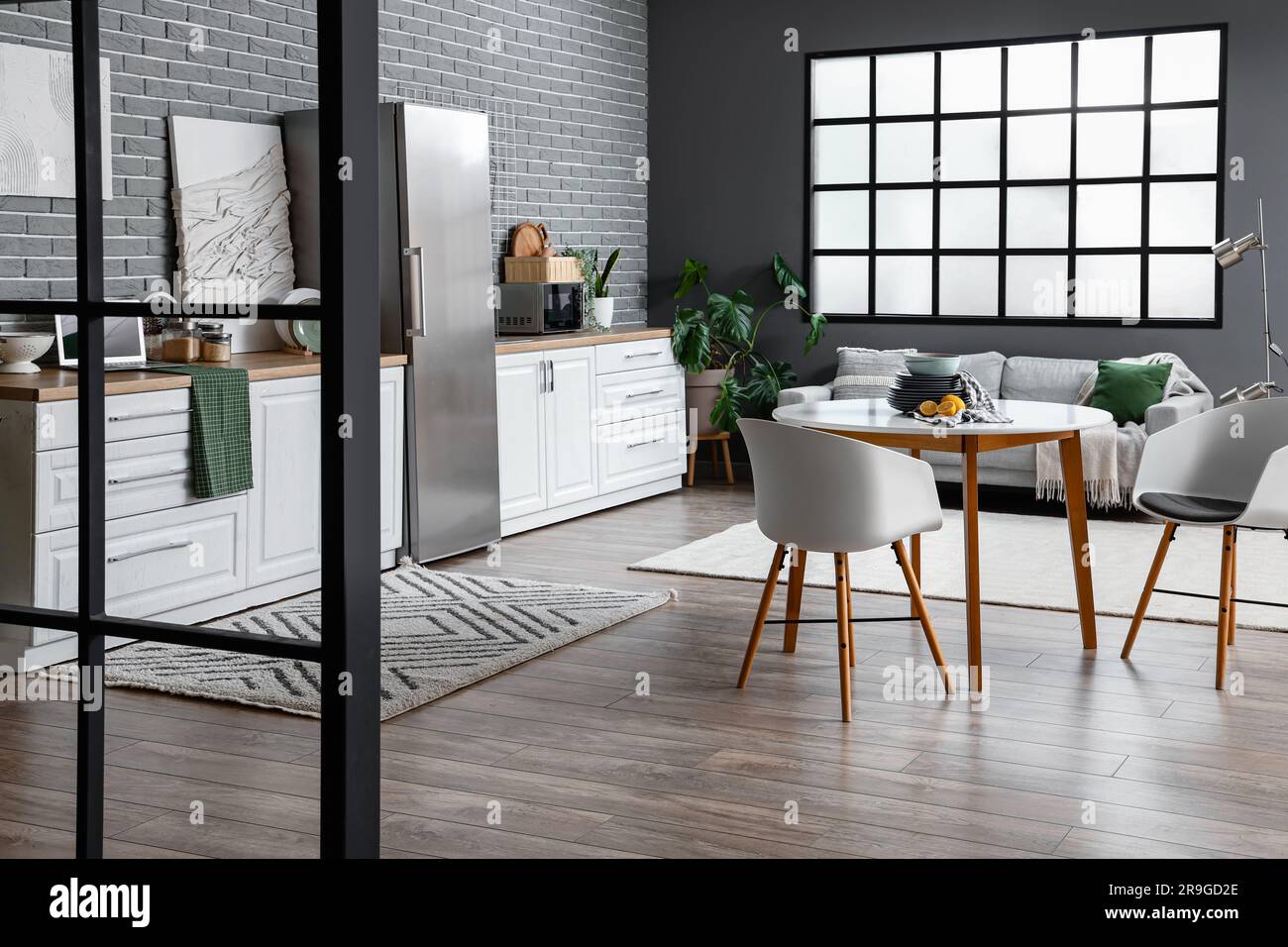 Interior of light kitchen with stylish fridge, counters, table and ...