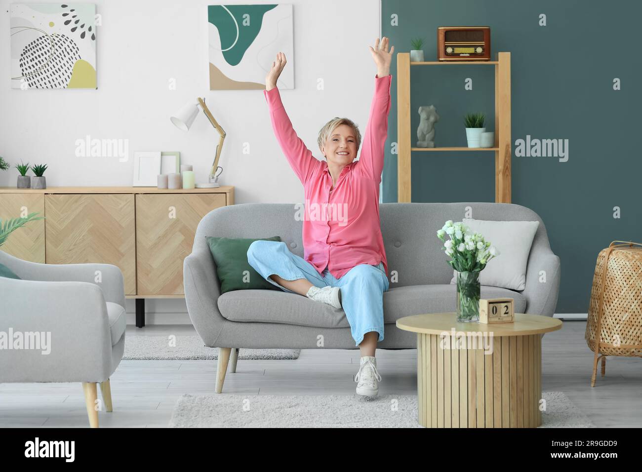 Happy mature woman sitting on sofa at home Stock Photo - Alamy