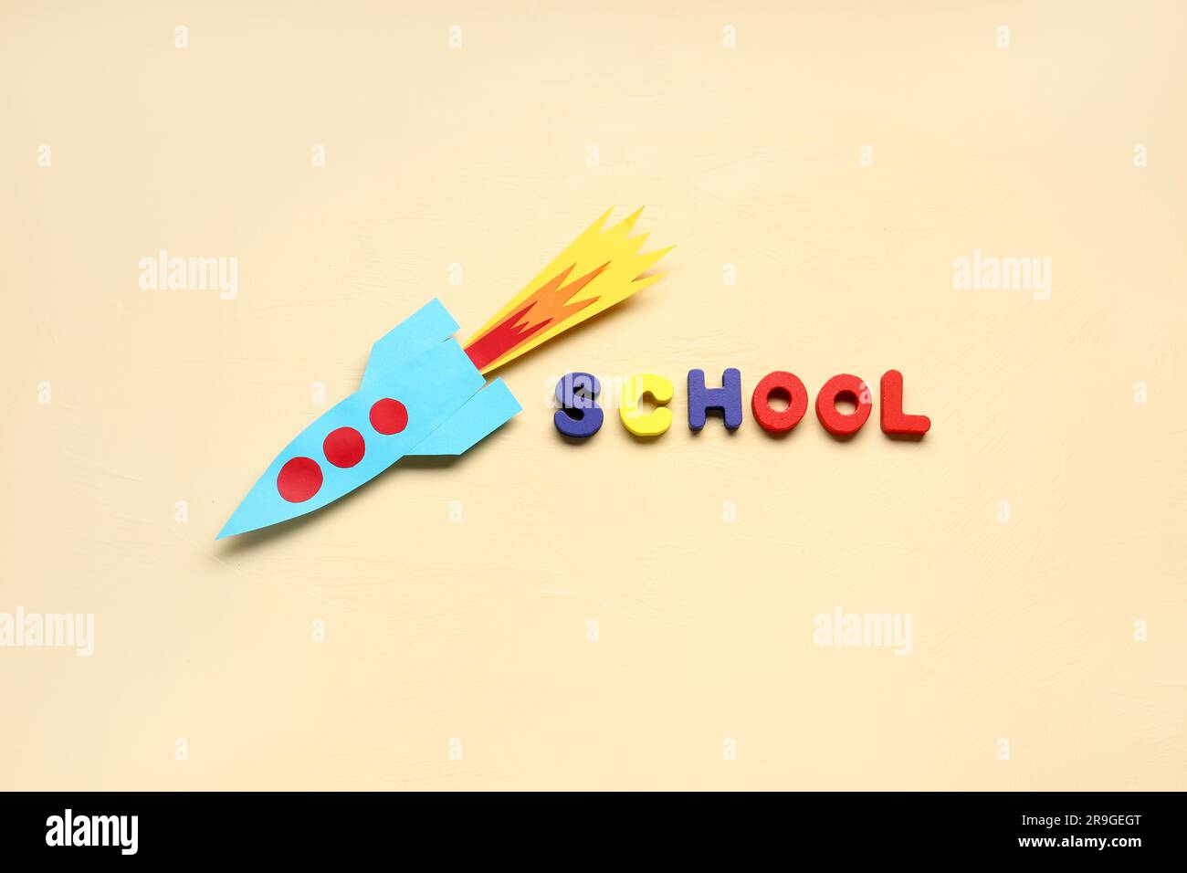 Paper rocket with word SCHOOL on beige background Stock Photo
