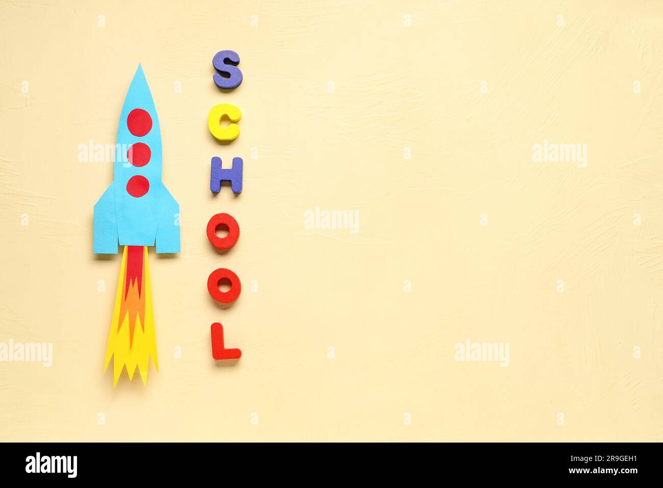 Paper rocket with word SCHOOL on beige background Stock Photo
