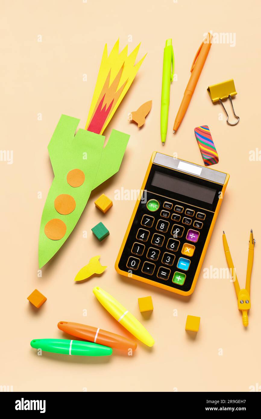 Paper color rockets with calculator, pens and compass on beige