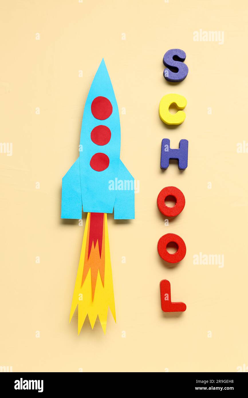 Paper rocket with word SCHOOL on beige background Stock Photo