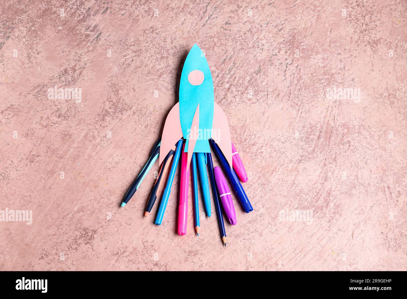 Paper Rockets Pink Blue paper rocket with pens, pencils and markers on pink grunge ...