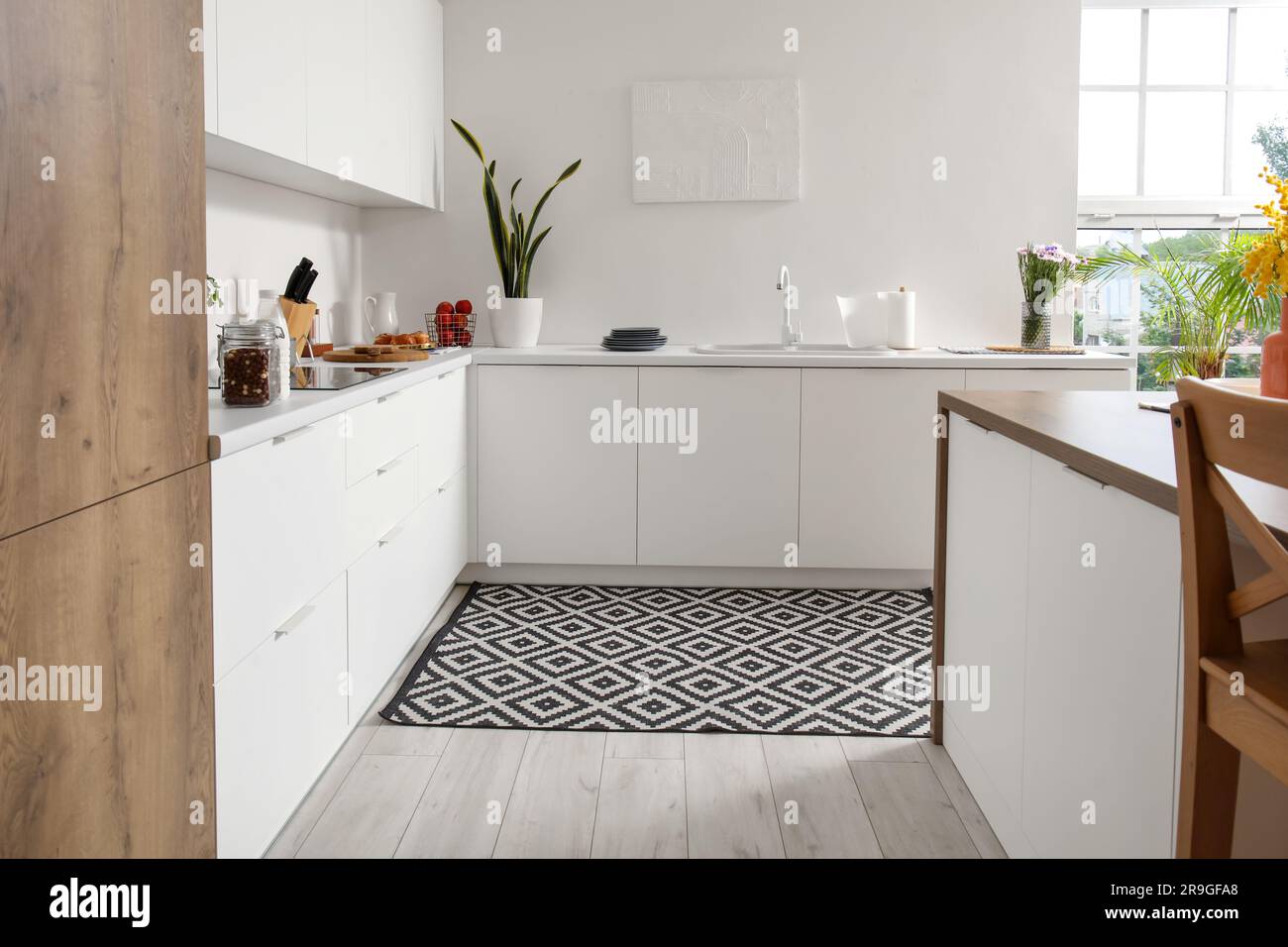 Interior of modern kitchen with white counters, electric stove and sink ...