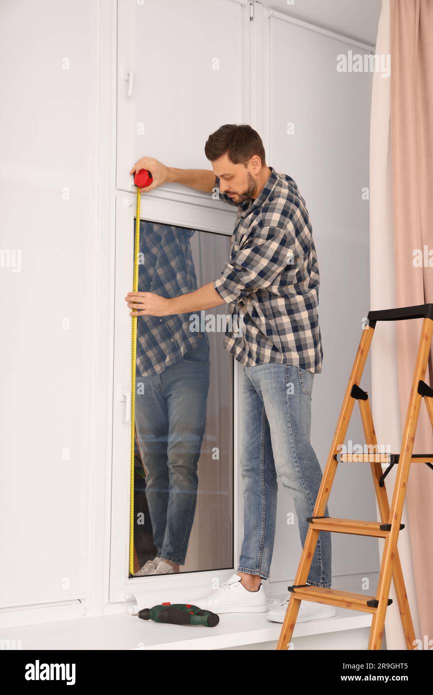 Man measuring window with tape indoors. Roller blinds installation ...