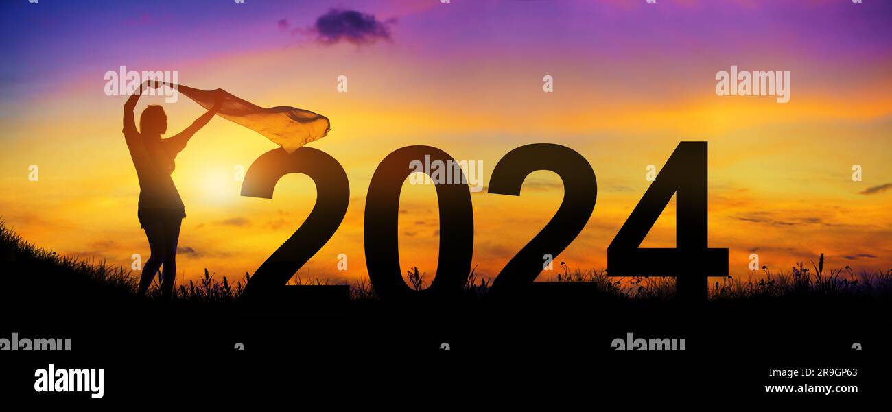 Welcome merry Christmas and Happy new year in 2024. Silhouette enjoying women flapping a thin fabric on the hill while celebrating 2024 years. Stock Photo