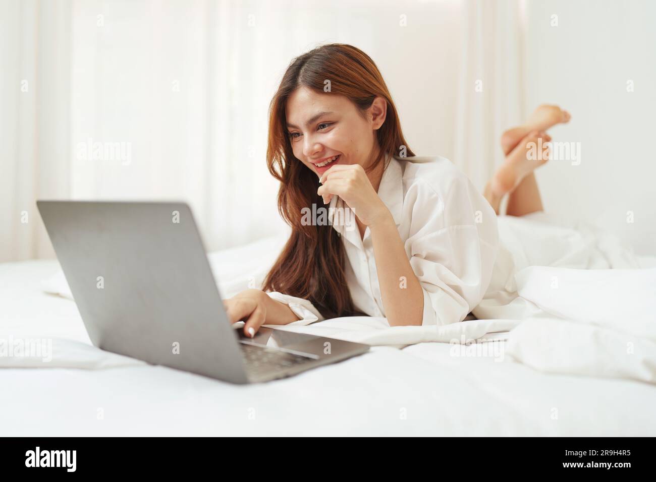 Happy smiling asian woman stretching on bed in the morning and using ...