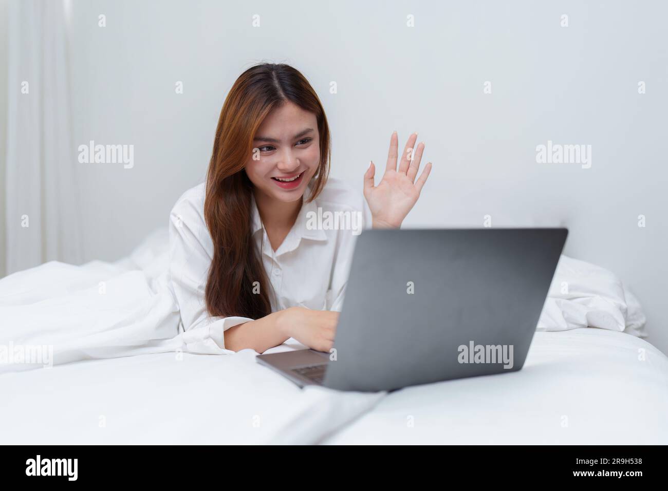 Happy smiling asian woman stretching on bed in the morning and using ...
