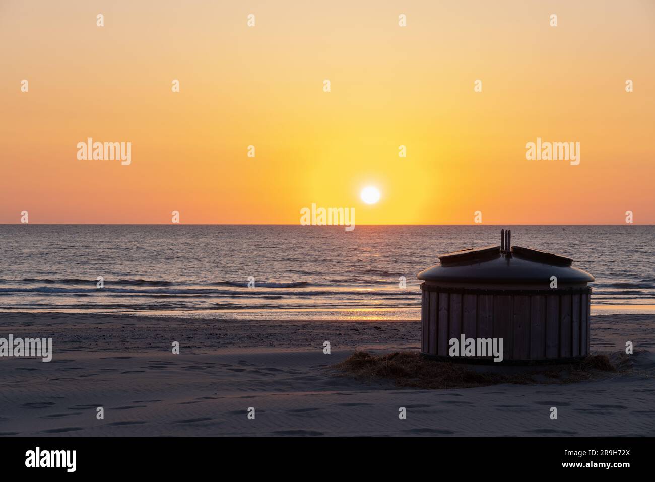 On this beautiful beach whit sunset, there is a trash can where people can deposit their dirt. Stock Photo