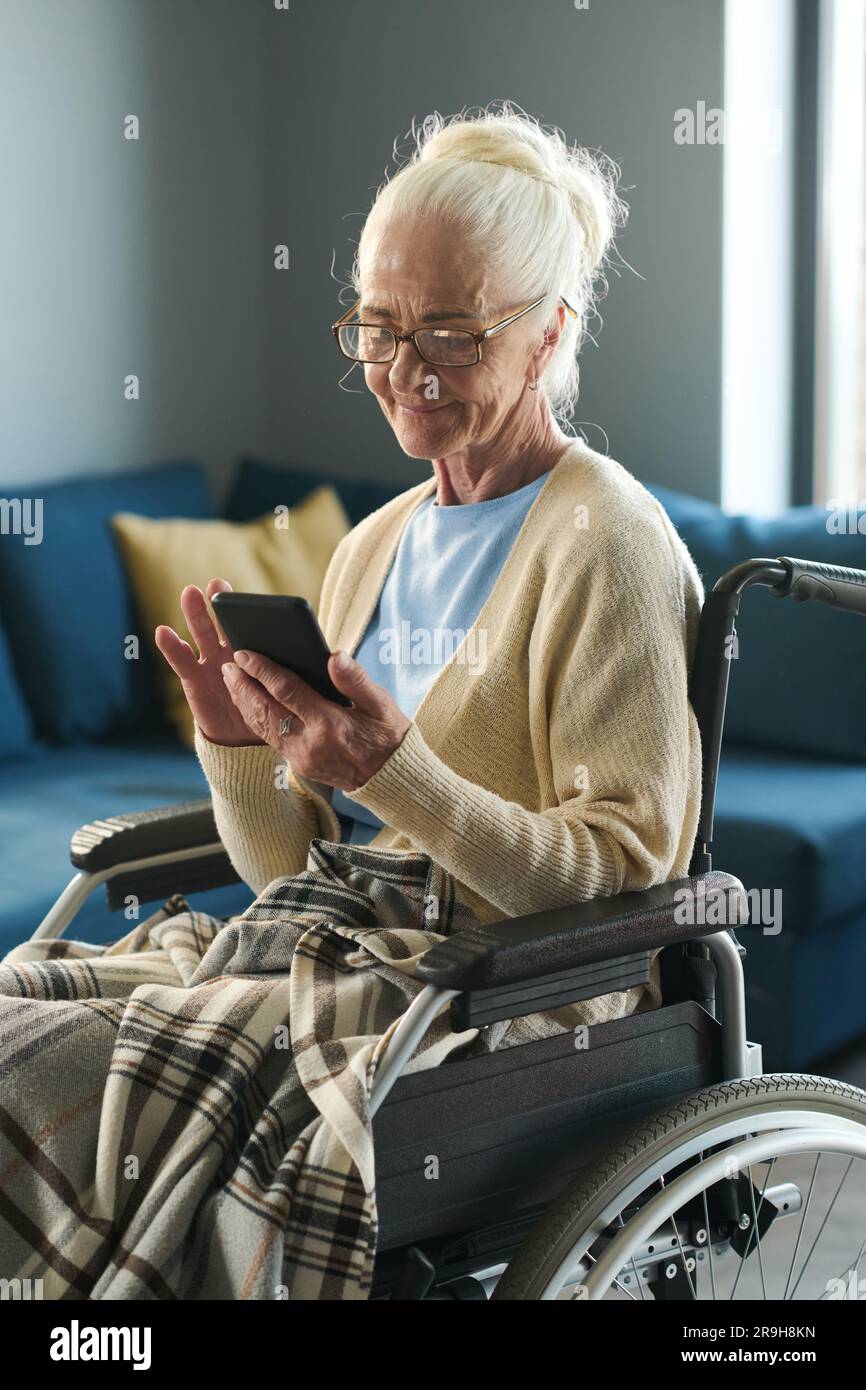 Silver society female representative with disability scrolling in mobile phone while sitting in