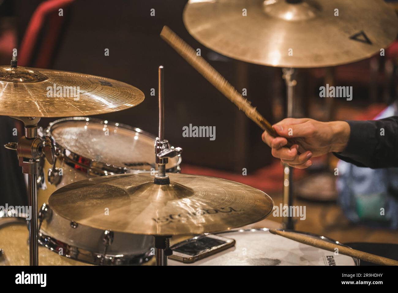 A drummer performing on a drum set, striking the drums and cymbals with
